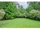 A spacious backyard features a lush green lawn surrounded by mature trees at 830 Montego Sw Way, Lilburn, GA 30047
