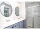 Bathroom with dual sinks, round mirrors, a tub/shower combo, and blue cabinets at 830 Montego Sw Way, Lilburn, GA 30047