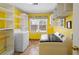 A yellow laundry room with tile flooring, a utility sink, washer, and dryer at 3521 Southern Bay Ct, Snellville, GA 30039