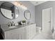 This bathroom offers a dual sink vanity with granite countertop, round mirrors, and neutral gray walls at 305 Thorntree Ln, Canton, GA 30115