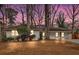 Charming single-story brick home nestled among mature trees with a well-manicured front yard and a twilight sky at 1119 Oakdale Se Dr, Smyrna, GA 30080