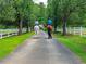 A picturesque view of horses being ridden down a tree-lined drive, alongside green lawns and white fencing at 1820 Walker Sw Rd, Conyers, GA 30094