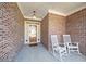 Inviting front porch featuring rocking chairs and brick flooring with wooden front door at 3377 Fielders Pt, Dacula, GA 30019