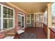 View of a cozy covered porch featuring brick, dark wood floors, and comfortable outdoor seating at 221 Aster Ct, Canton, GA 30114
