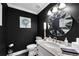 Stylish half bathroom with modern fixtures, a round mirror and dark accent walls at 54 Basswood Cir, Atlanta, GA 30328