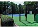 Gated tennis court with green and blue surface surrounded by lush greenery at 54 Basswood Cir, Atlanta, GA 30328