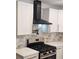 Modern kitchen features sleek black vent hood, white cabinets, marble backsplash, and stainless steel gas range at 2358 Tilson Rd, Decatur, GA 30032