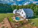 Aerial view of a white farmhouse-style home with a pool, a detached garage, and a spacious lawn at 2731 Tribble Mill Rd, Lawrenceville, GA 30045