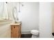 A bathroom boasts a wooden vanity, round sink, oval mirror, and modern toilet against white walls at 2731 Tribble Mill Rd, Lawrenceville, GA 30045