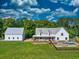A white farmhouse-style home with a metal roof, a detached garage, a pool, and a large, grassy yard at 2731 Tribble Mill Rd, Lawrenceville, GA 30045