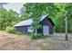 Outbuilding with an American flag and rolling metal door, surrounded by lush greenery at 2731 Tribble Mill Rd, Lawrenceville, GA 30045