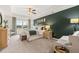Spacious bedroom featuring a tray ceiling, fan, green accent wall, sitting area, and natural light from the window at 353 Sound Cir, Stockbridge, GA 30281