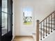 Bright foyer featuring hardwood stairs with iron railings, a large black front door, and a view to the front yard at 200 Heatherton Way, Milton, GA 30009