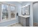 Bright bathroom with gray vanity, marble countertop, ample natural light from two windows and light blue wall paint at 5450 Taylor Rd, Johns Creek, GA 30022