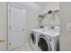Bright laundry room featuring a white washer and dryer, a wire shelf, and a white door at 5450 Taylor Rd, Johns Creek, GA 30022