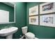 Stylish powder room features a pedestal sink, a toilet, and decorative artwork against an attractive green wall at 301 Sound Cir, Stockbridge, GA 30281