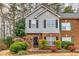 Charming two-story townhome with gray siding, red brick, a black door and manicured landscaping at 4405 Maple Valley Dr, Cumming, GA 30040