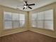 Bright bedroom featuring neutral carpeting, paint, and updated ceiling fan, with natural light from two large windows at 7972 Applemist Dr, Fairburn, GA 30213