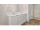 Bright bathroom with a double sink vanity, white cabinets, and wood look flooring at 297 Sound Cir, Stockbridge, GA 30281