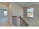 Bright hallway featuring wood and metal railing, neutral paint, and a view of another room at 628 Leafy Branch Way, Mcdonough, GA 30253