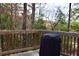 A wooden back deck with a grill, surrounded by trees and nature at 2127 Dodson Woods Dr, Fairburn, GA 30213