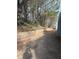 Backyard featuring a brick retaining wall and mature trees at 4815 Diggers Way, Sugar Hill, GA 30518