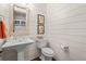 Charming half bath featuring shiplap walls, pedestal sink, decorative mirror, and vintage artwork at 2109 Rocky Falls Nw Ct, Kennesaw, GA 30152