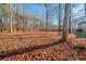 A spacious backyard covered with fallen leaves and surrounded by tall trees at 2400 Stedman Sw Ln, Conyers, GA 30094