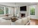 Cozy living room with a fireplace, hardwood floors, and large windows overlooking the backyard at 3180 Arden Nw Rd, Atlanta, GA 30305