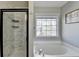 Bright bathroom with marble tile shower and soaking tub under a large window at 221 Kenninghall Se Ln, Smyrna, GA 30082