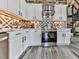 Well-equipped kitchen with stainless steel oven, white cabinets, and decorative backsplash at 255 Marks Way, Canton, GA 30115