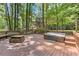 Relaxing back deck with a built in hot tub, stone fireplace and benches surrounded by lush green trees at 4259 Arbor Club Dr, Marietta, GA 30066