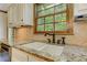 Close up of kitchen sink with bronze fixtures and granite counters with natural light from the window at 4259 Arbor Club Dr, Marietta, GA 30066
