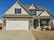Two-story house with stone accents and a three-car garage at 1455 Weeping Tree Cir, Auburn, GA 30011