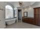 Bright bathroom featuring a soaking tub beneath a large arched window and a glass-enclosed shower at 4011 Charrwood Trce, Marietta, GA 30062