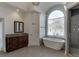 Bright bathroom featuring a soaking tub beneath a large arched window and a glass-enclosed shower at 4011 Charrwood Trce, Marietta, GA 30062