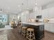 Open-concept kitchen features a dark island with stool seating, white cabinets, and modern lighting fixtures at 405 Nettle Ct, Woodstock, GA 30188