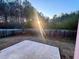 Sun-drenched back yard featuring a concrete patio area, bordered by a wooden fence and mature trees at 4547 Carriage Park Dr, Lithonia, GA 30038