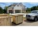 Two-story home with a three-car garage featuring light-colored brickwork with construction dumpsters in the front at 679 Crest Line Trl, Powder Springs, GA 30127