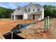 New construction home with white brick, gable roof, covered porch, and partially landscaped yard at 679 Crest Line Trl, Powder Springs, GA 30127