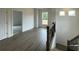 Bright hallway with gray wood flooring leading to an open doorway and staircase at 679 Crest Line Trl, Powder Springs, GA 30127