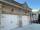 Two car garage featuring paneled doors with decorative black hardware and an elegant brick and stone facade at 1320 Newbridge Cir, Buford, GA 30519