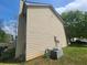 Tan house exterior with AC unit and partial view of a yard and trees at 5789 Star Flower Dr, Ellenwood, GA 30294