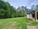Backyard view featuring a spacious lawn bordered by lush trees, offering privacy and room for outdoor activities at 130 West Lake Blvd, Carrollton, GA 30116