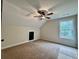 Bedroom featuring neutral carpet, a modern ceiling fan and a window, plus a closet with a black door at 130 West Lake Blvd, Carrollton, GA 30116