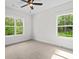 Bright bedroom featuring plush carpet, a ceiling fan, and plenty of natural light from the two large windows at 130 West Lake Blvd, Carrollton, GA 30116