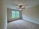 Bright bedroom with neutral carpeting, a ceiling fan, and a window with a view of trees at 130 West Lake Blvd, Carrollton, GA 30116