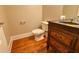 Powder room features wood flooring, vanity with dark wood cabinet, and white toilet at 6310 Talking Tree Ct, Cumming, GA 30028
