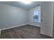 Neutral bedroom featuring wood-look flooring, a window, and a white door at 6310 Talking Tree Ct, Cumming, GA 30028