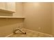 Beige tiled laundry room featuring overhead cabinet, shelf, and washer hookups at 6310 Talking Tree Ct, Cumming, GA 30028